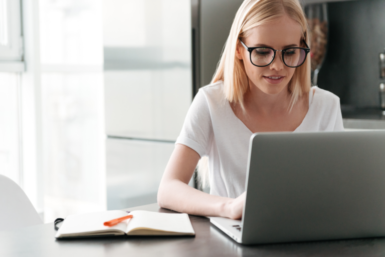 Young lady sitting at a desk, working on a laptop.