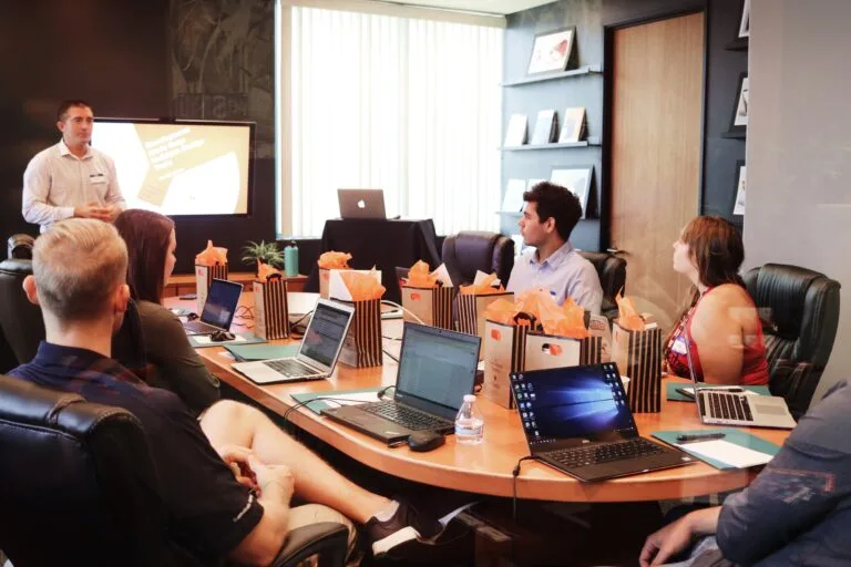 A corporate training session with participants and a presenter in a conference room.