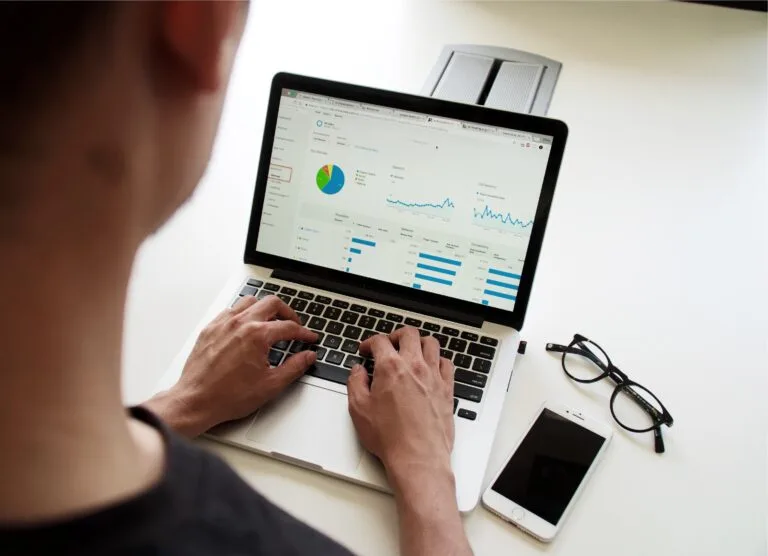 Professional analyzing performance metrics on a laptop with analytical graphs on the screen.