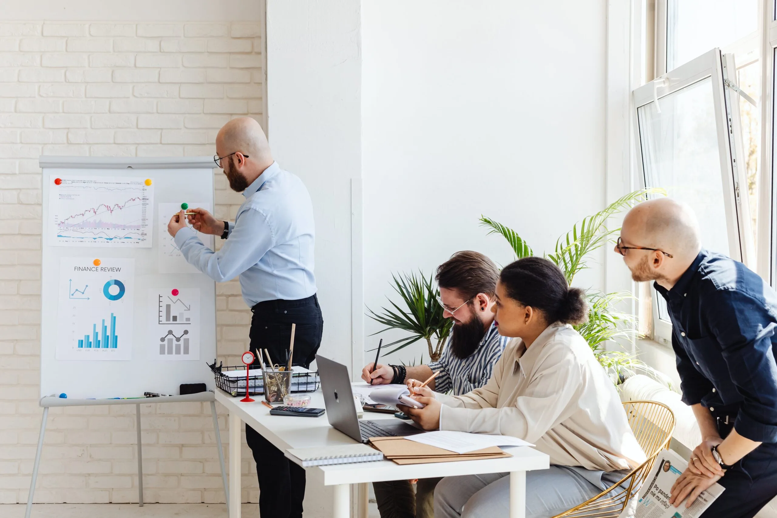 Business team attentively reviews financial trends on a whiteboard during a strategic planning session.