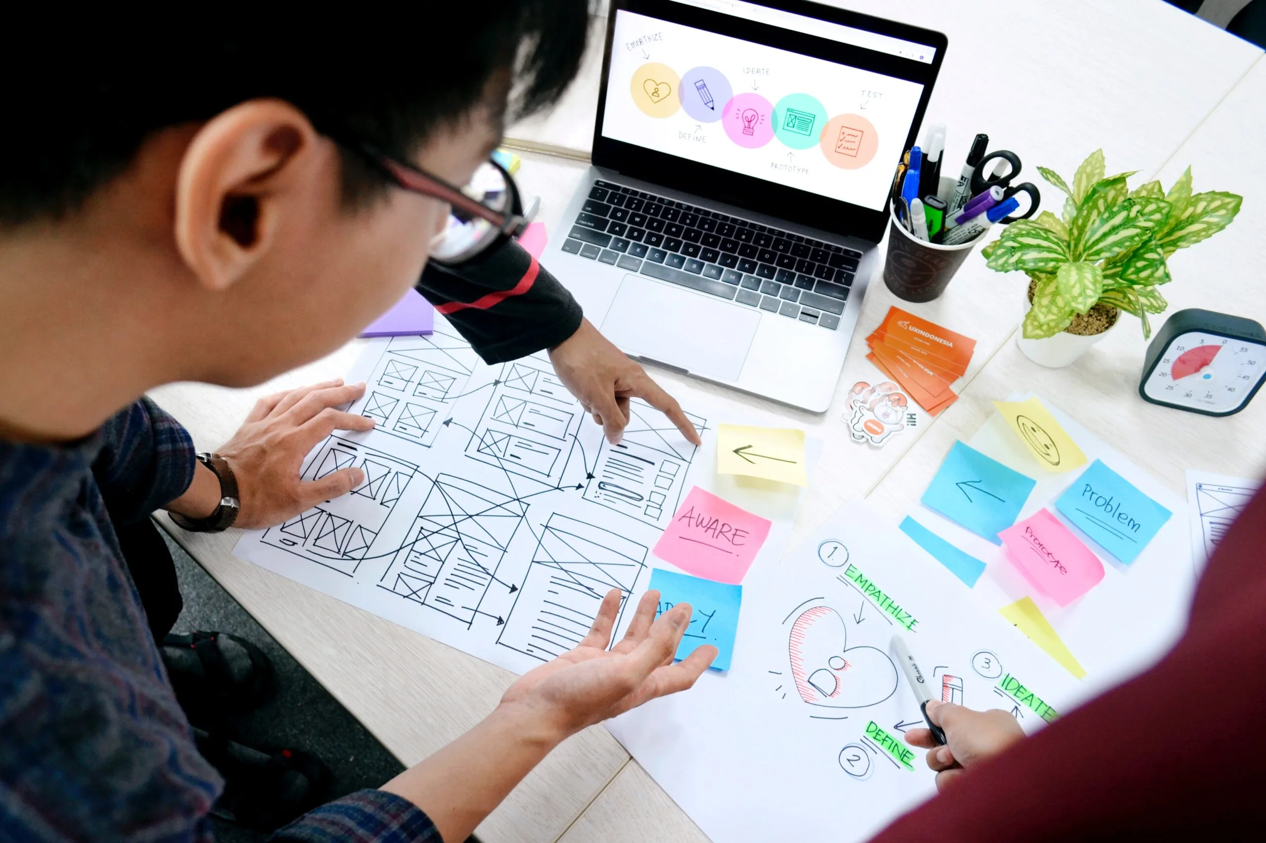 Business professionals discussing over wireframes and colorful sticky notes on a design planning session